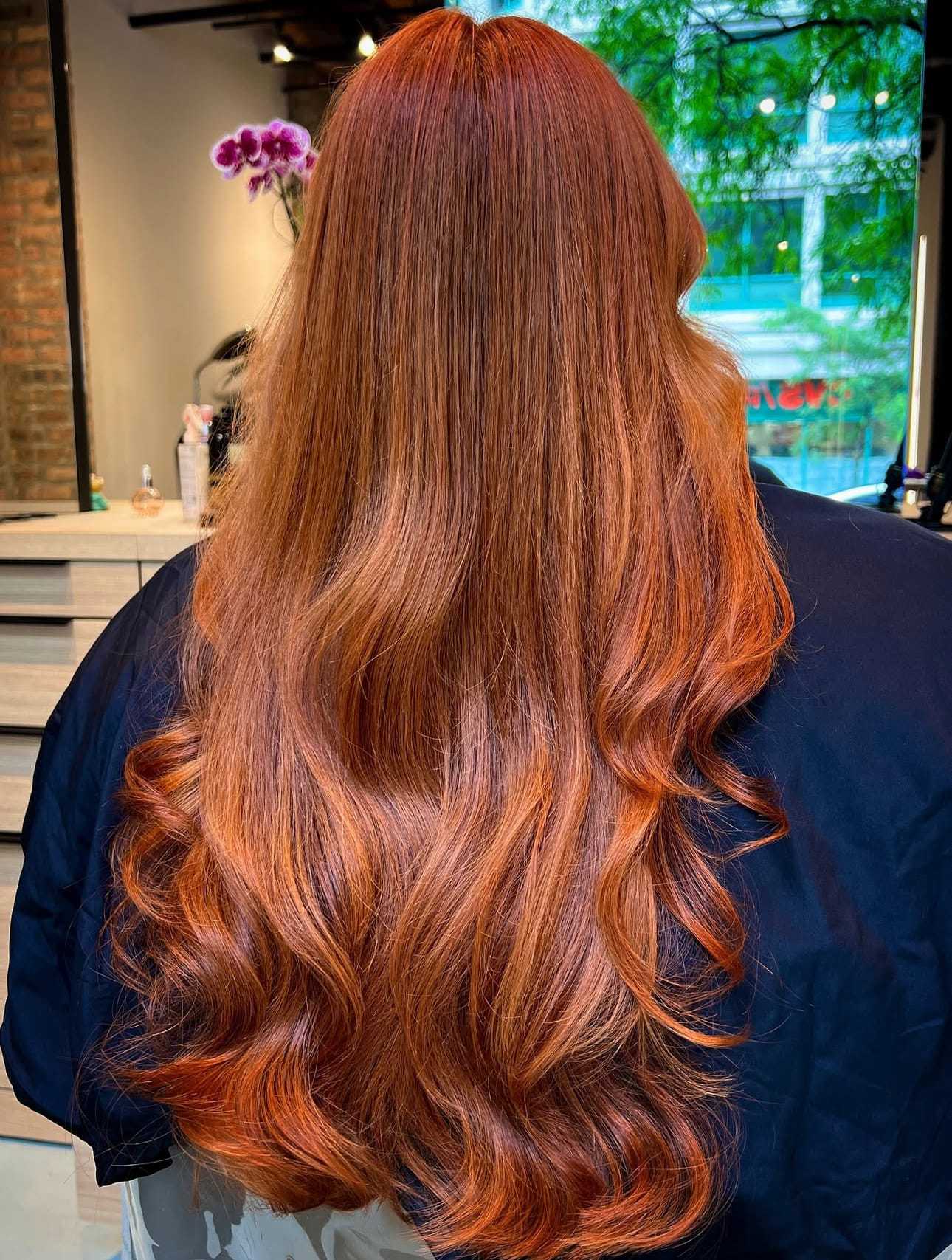 Long, wavy red hair cascading down the back in a salon setting.