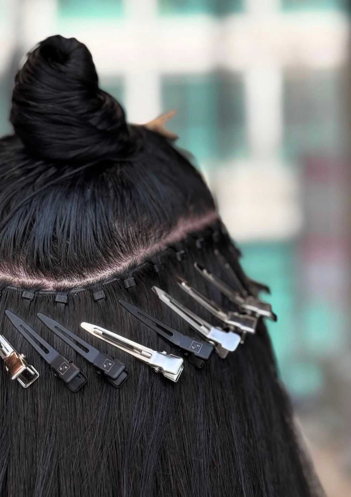 Hair extensions in process with clips and bun showing application technique.