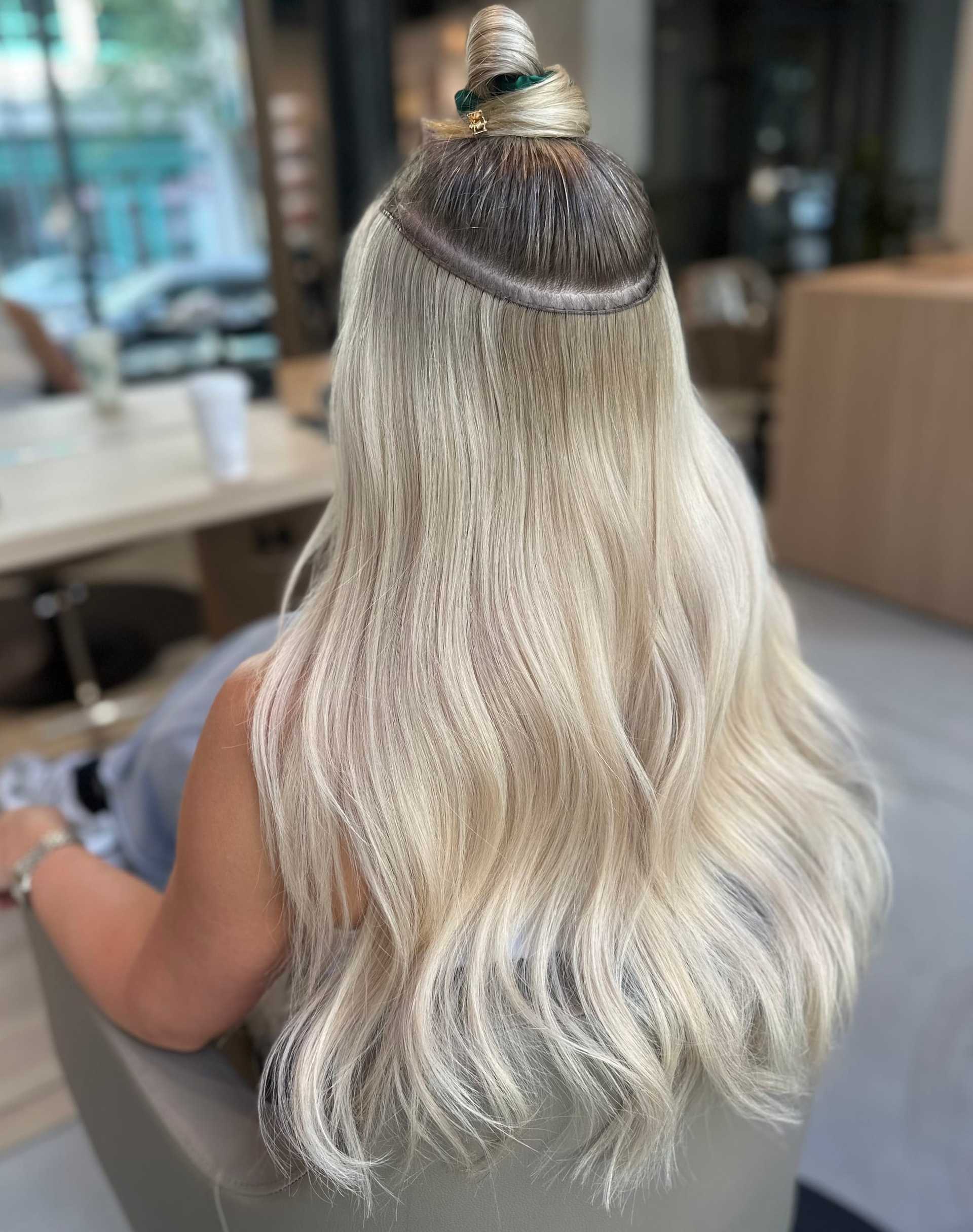 Blonde hair with extensions being styled in a salon.