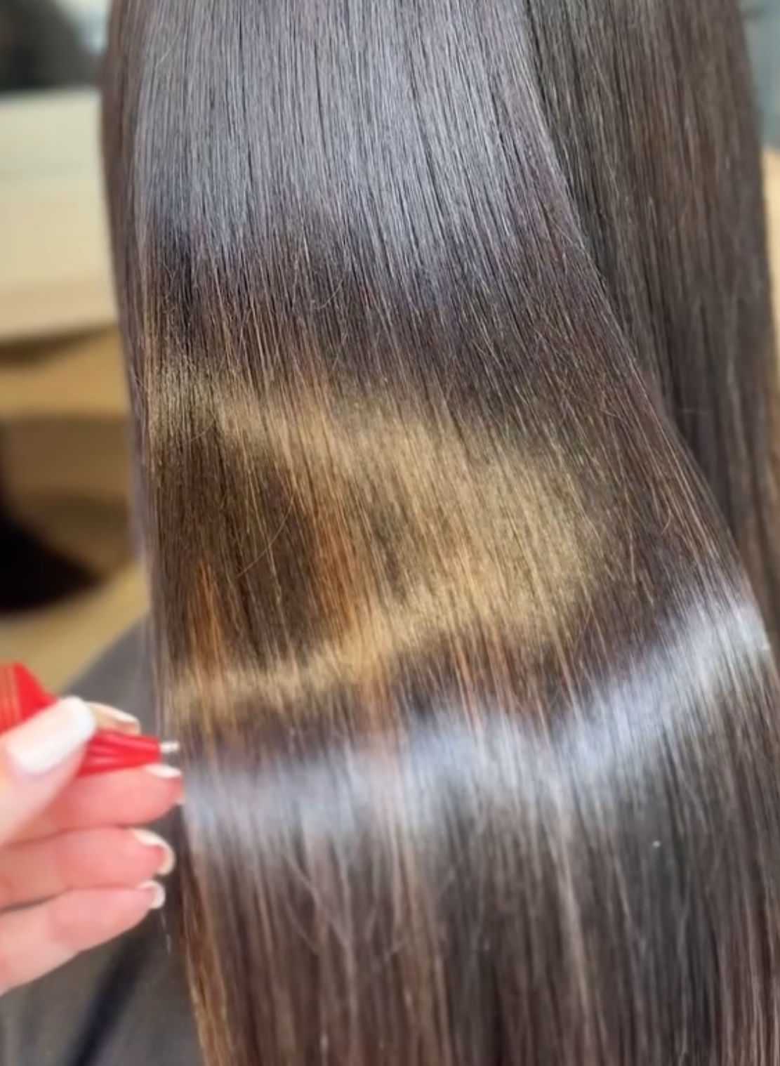 Shiny brown hair with subtle highlights being styled with a red comb.